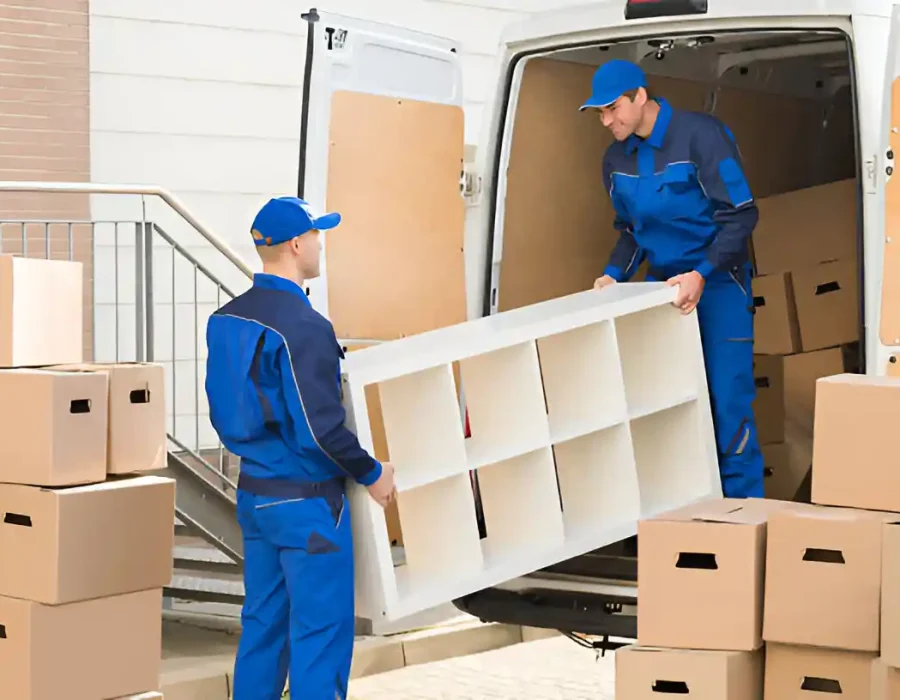 Removal team loading white shelving unit into truck with stacked boxes during cleanout service