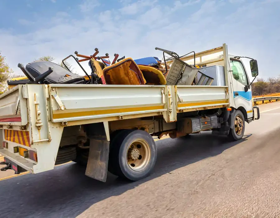 Commercial removal truck with uniformed workers loading construction debris and materials using hand truck equipment
