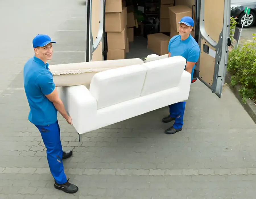Two movers transporting a sofa from a van for debris removal and site cleanup services