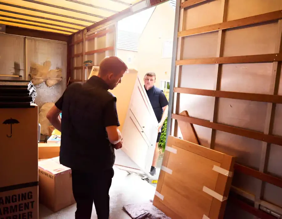 Two movers carefully transporting furniture from a truck for efficient relocation and cleanup services