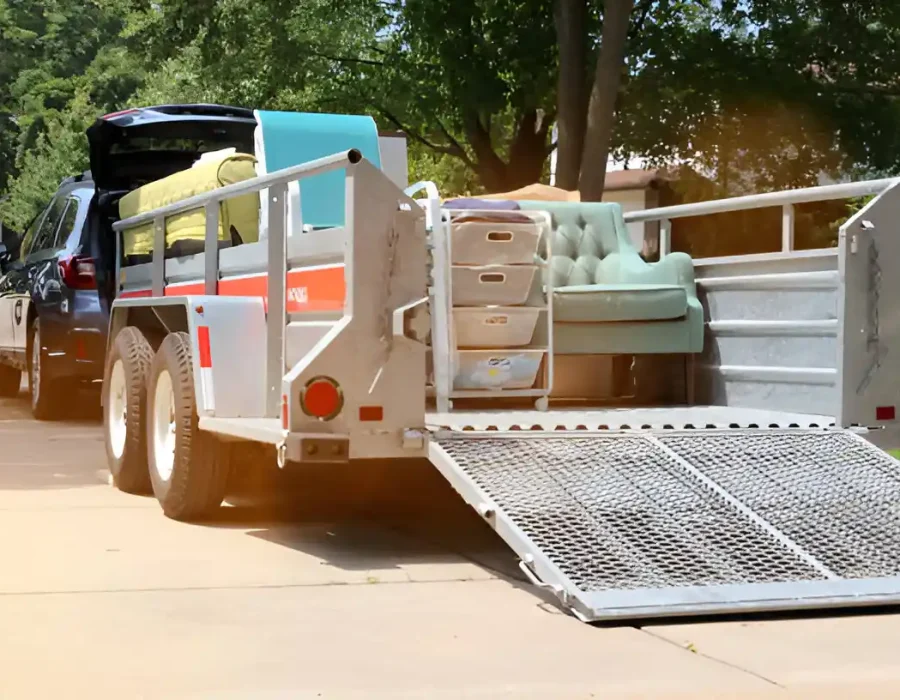 Professional movers loading furniture into truck using hand truck and loading ramp for efficient removal service