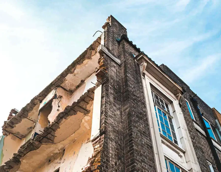 View of a damaged building showing debris from demolition, highlighting site conditions.