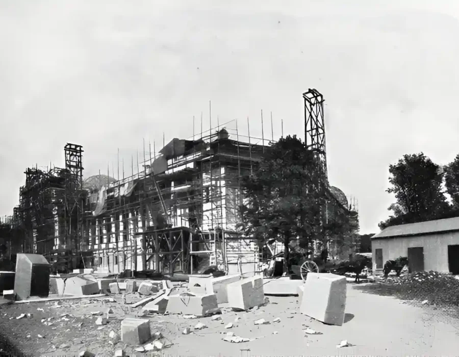 Partially demolished building with scaffolding and stone debris scattered on the ground.