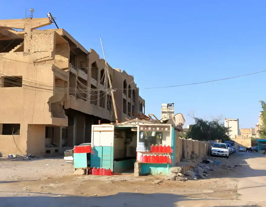 Partially demolished building with debris and small roadside shop in urban area.