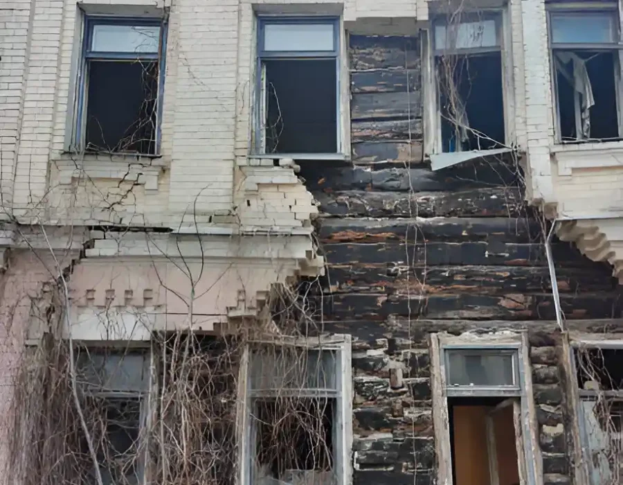 Deteriorating brick building with structural damage, fallen debris, and damaged windows ready for demolition