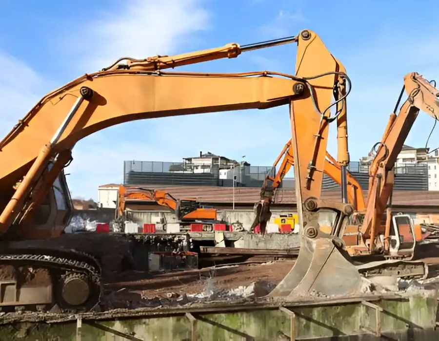 Multiple orange excavators preparing site for demolition with urban backdrop