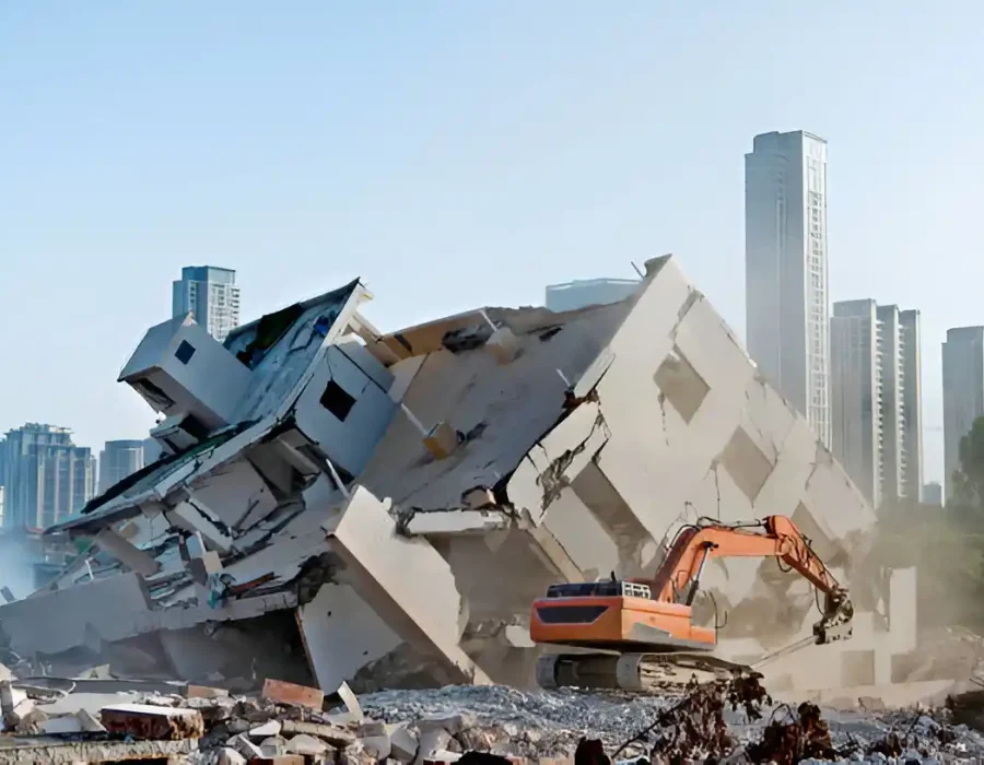 Excavator Demolishing Large Concrete Structure with City Skyline Background