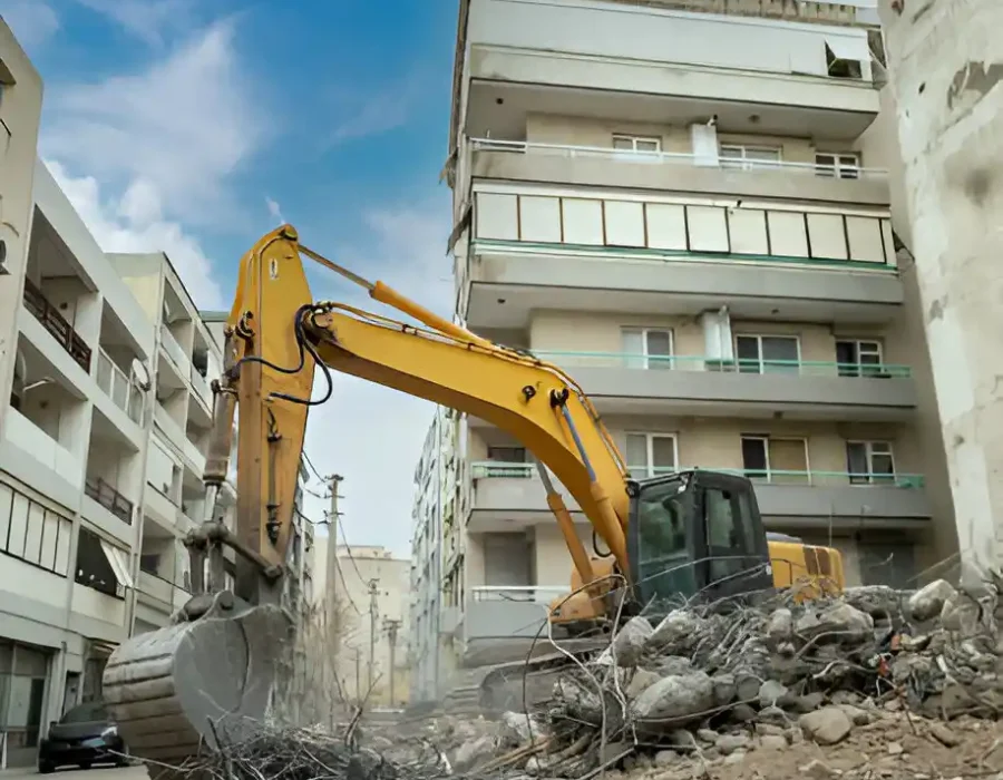 Yellow excavator demolishing multi-story apartment complex, urban renewal project