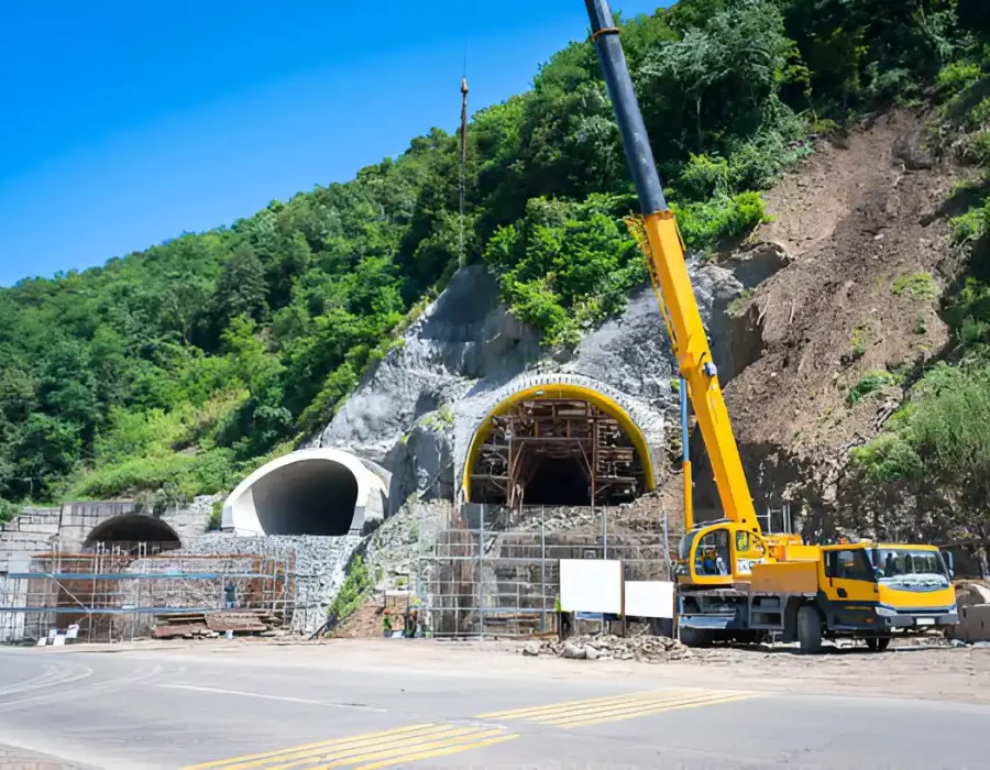 Yellow crane and truck at mountain tunnel site, infrastructure development project