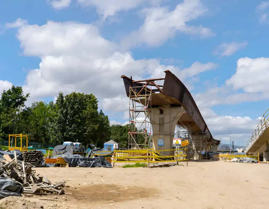 Construction site showing partial bridge demolition with scaffolding, safety barriers and debris piles
