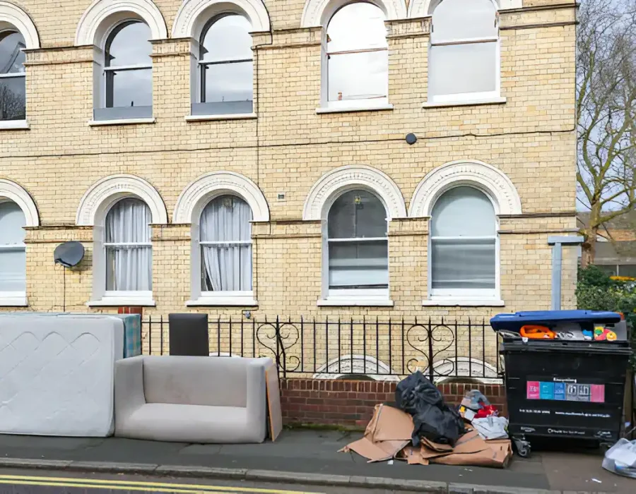 Discarded sofa and household waste on city street awaiting professional waste collection service
