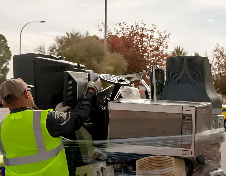 Worker in safety vest loading electronic waste and office equipment for specialized disposal service