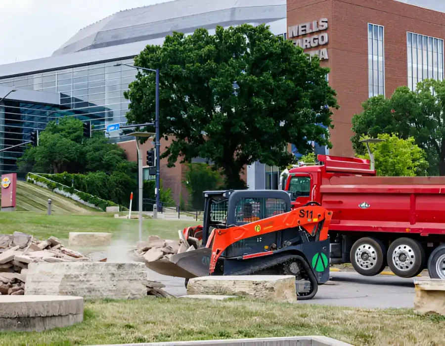 Skid steer and dump truck removing concrete debris during commercial site demolition project