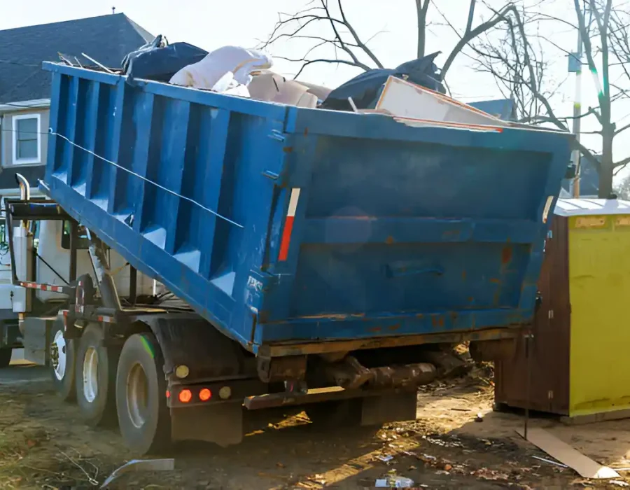 Blue roll-off container on dump truck for construction waste removal and hauling services