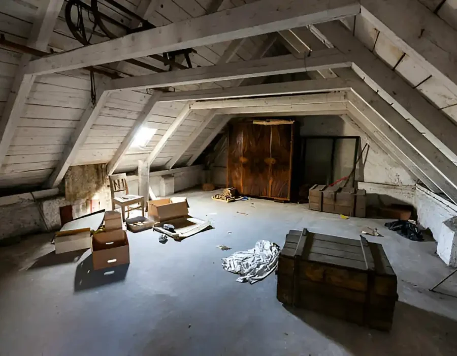Old attic space with scattered boxes and furniture requiring professional cleanout services