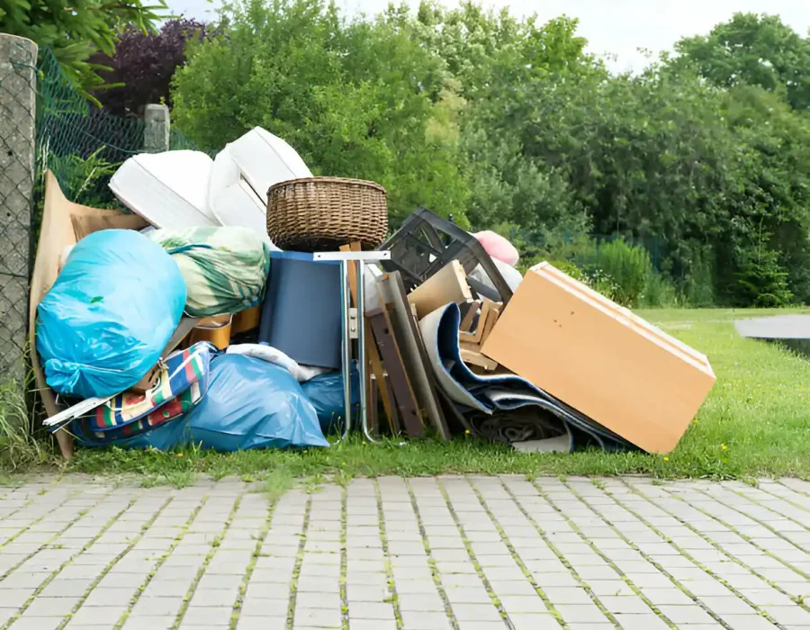 Mixed household items and furniture piled on patio requiring urgent waste removal services