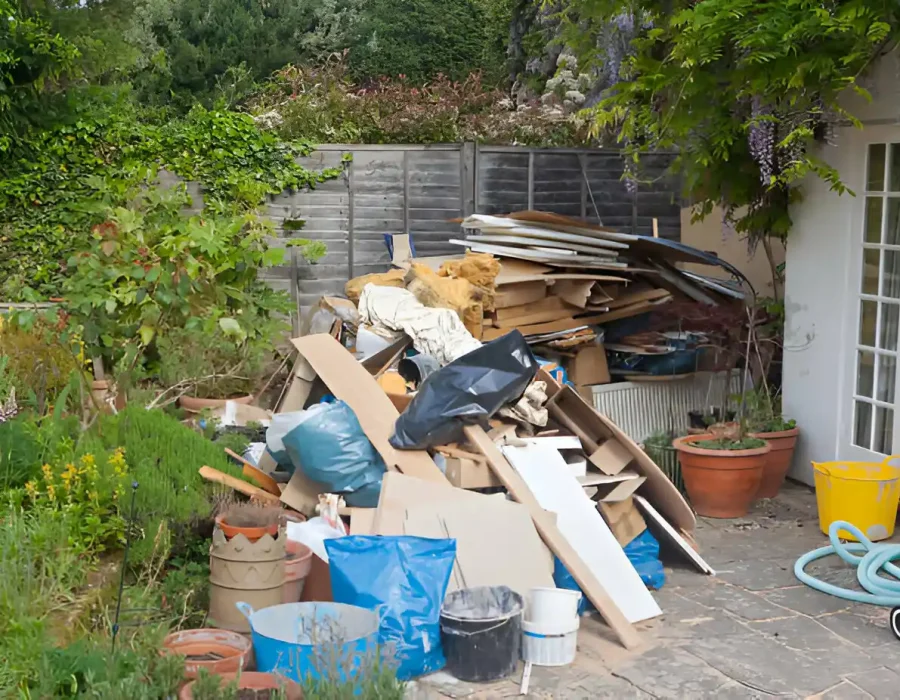 Mixed construction waste and renovation debris piled in garden area needing removal service
