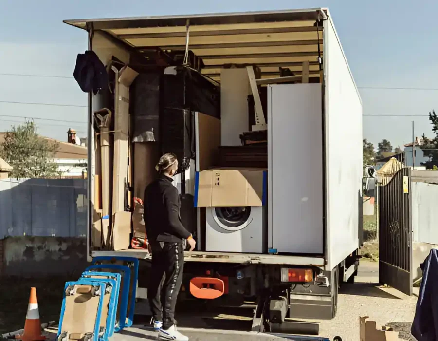 Professional hauler loading washer and household items into removal truck during cleanout