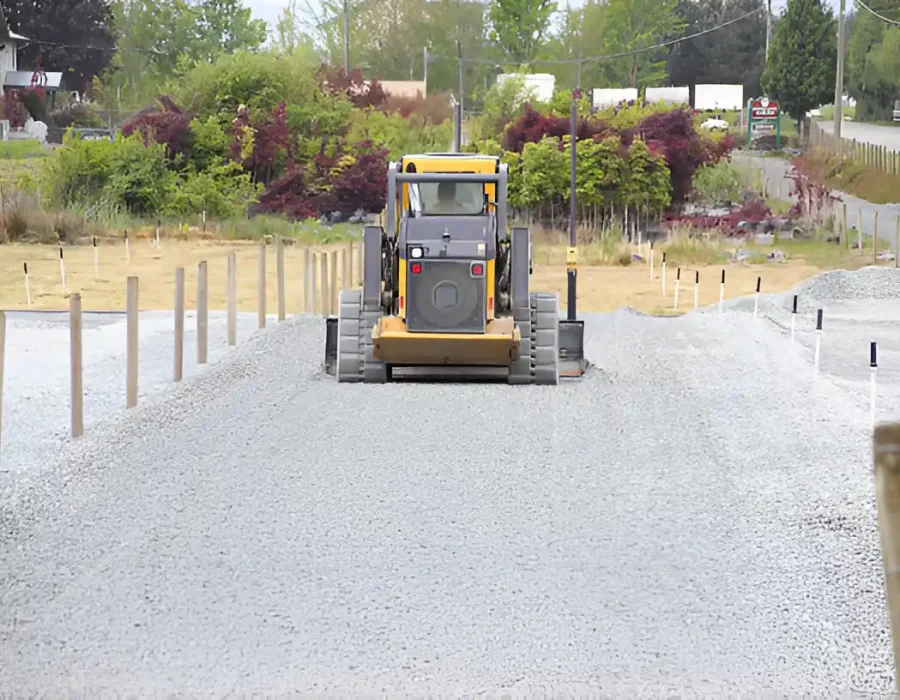 Grader leveling gravel for site preparation and debris removal in construction area