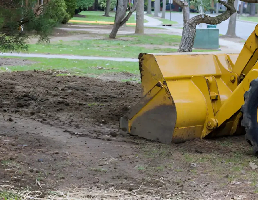 Heavy-duty loader performing site preparation and debris removal at residential property with excavation bucket