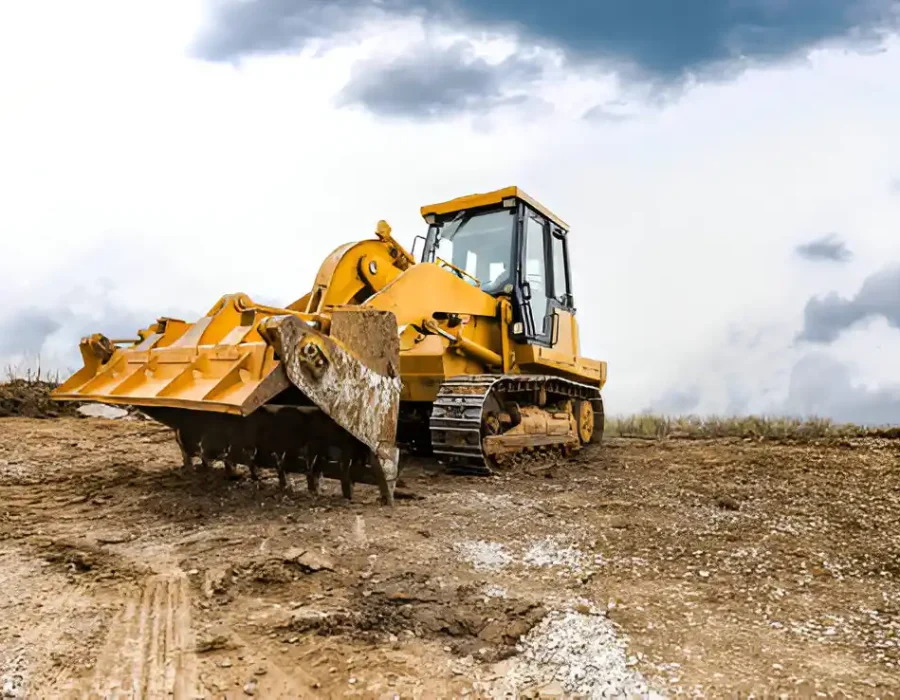 Industrial bulldozer performing site preparation and demolition work on muddy terrain under cloudy sky