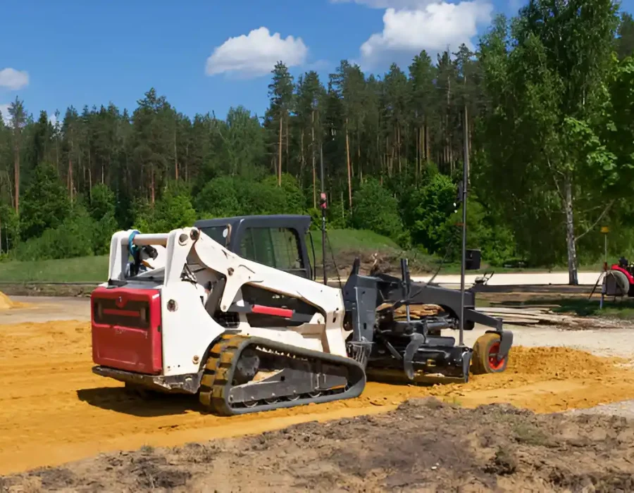 Skid steer loader leveling sand for site preparation and debris removal in construction area