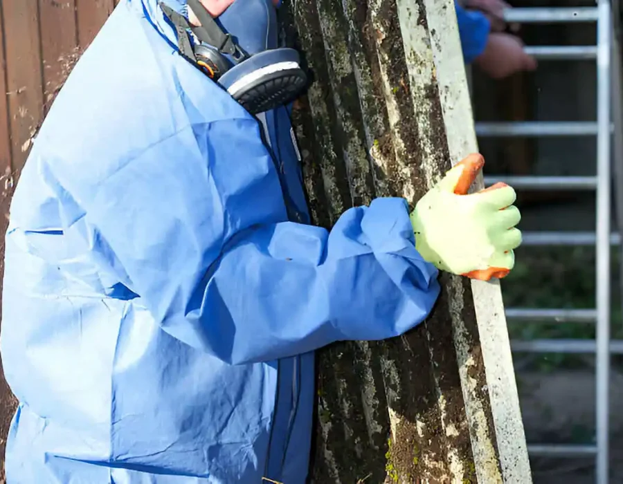 Laborer in protective gear carries debris during site cleanup and demolition efforts