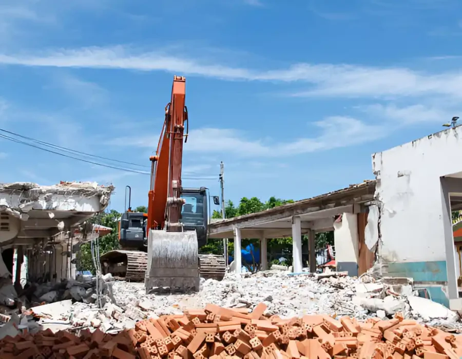 Orange excavator at demolition site with sorted brick pile and concrete debris removal