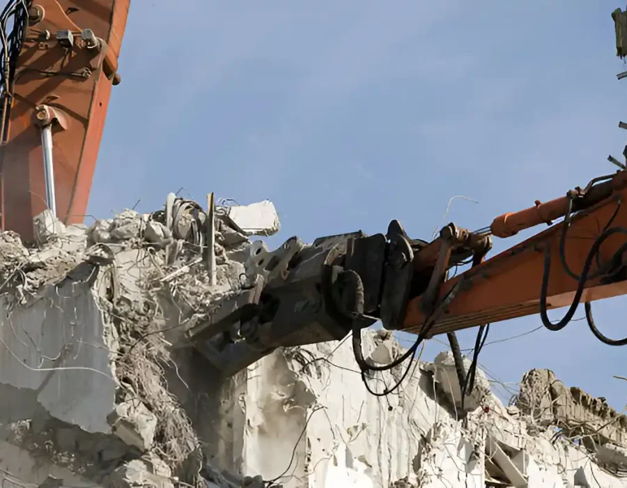 Close-up of hydraulic breaker attachment demolishing reinforced concrete structure