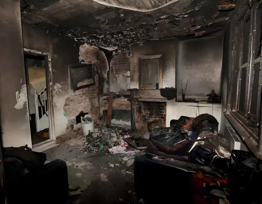 Severely burned interior room with extensive smoke damage and debris aftermath