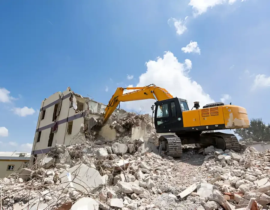 Yellow tracked excavator dismantling multi-story structure, professional demolition service