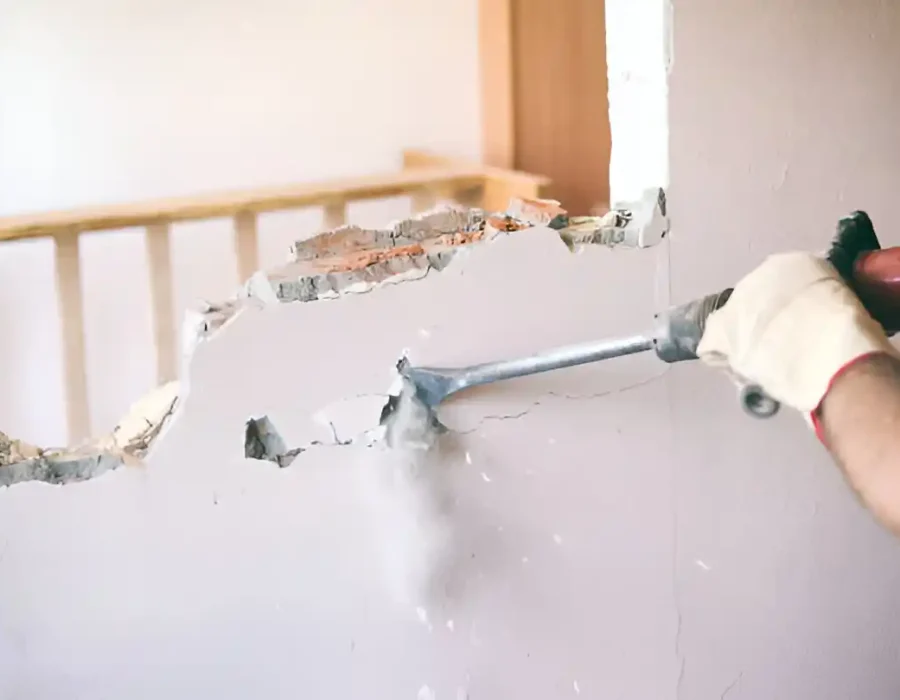 Hammer breaking drywall, interior renovation and demolition process closeup