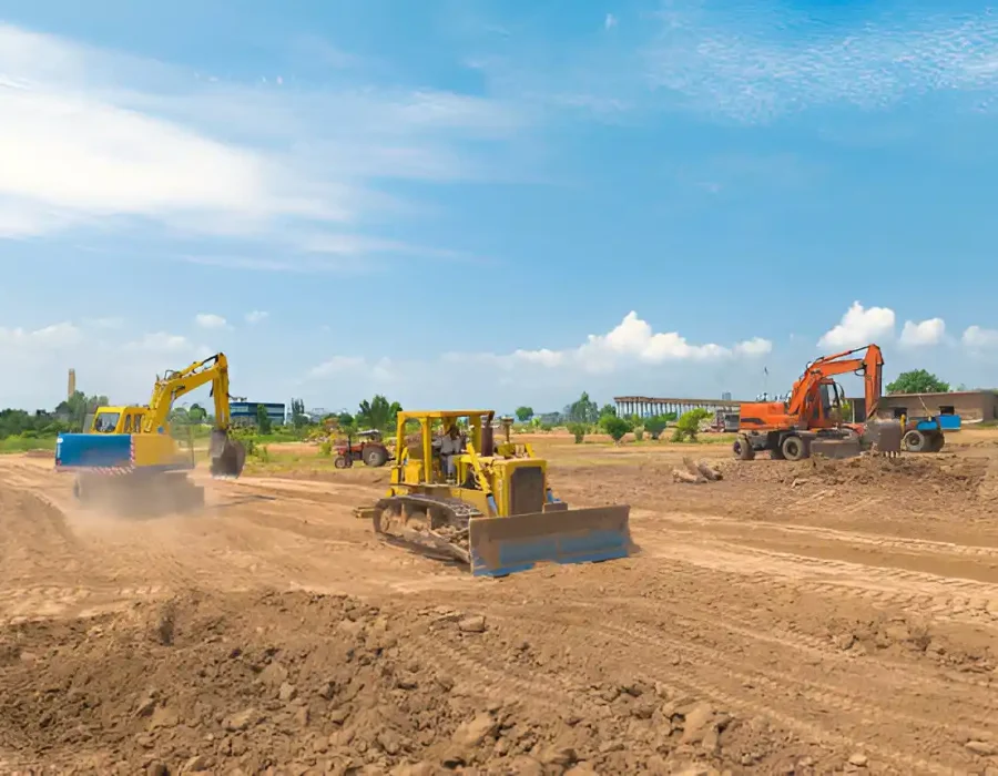 Multiple yellow and orange excavators and bulldozers working on dirt site