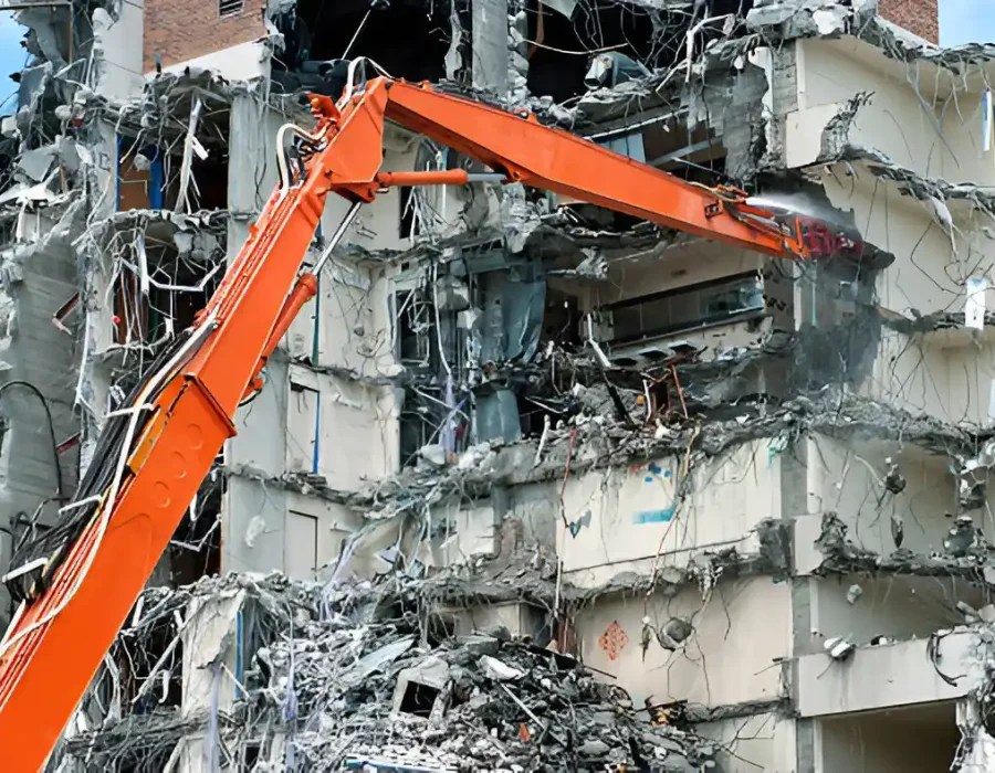 Orange demolition excavator with extended boom demolishing multi-story building structure