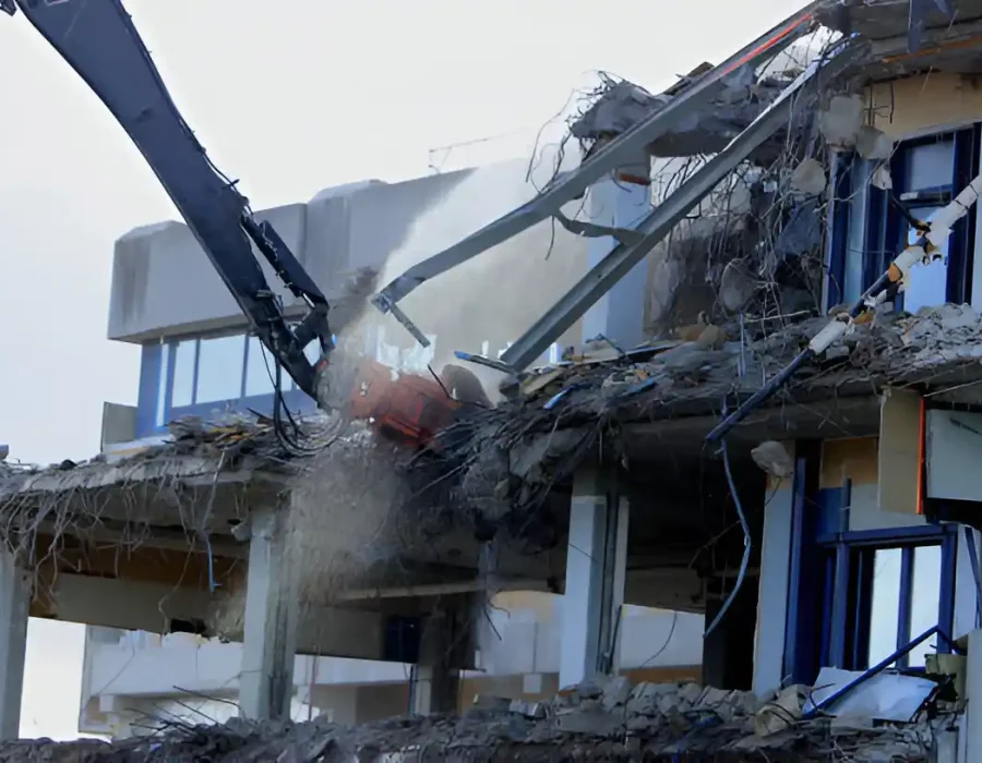 Two excavator arms demolishing concrete structure with precision control and dust suppression