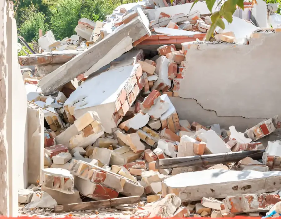 Collapsed interior walls showing brick, concrete, and drywall debris from structural demolition
