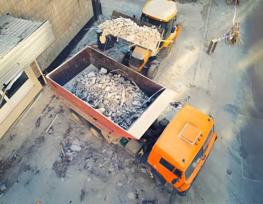 Overhead shot of dump truck loading demolition waste and concrete rubble at construction cleanup site