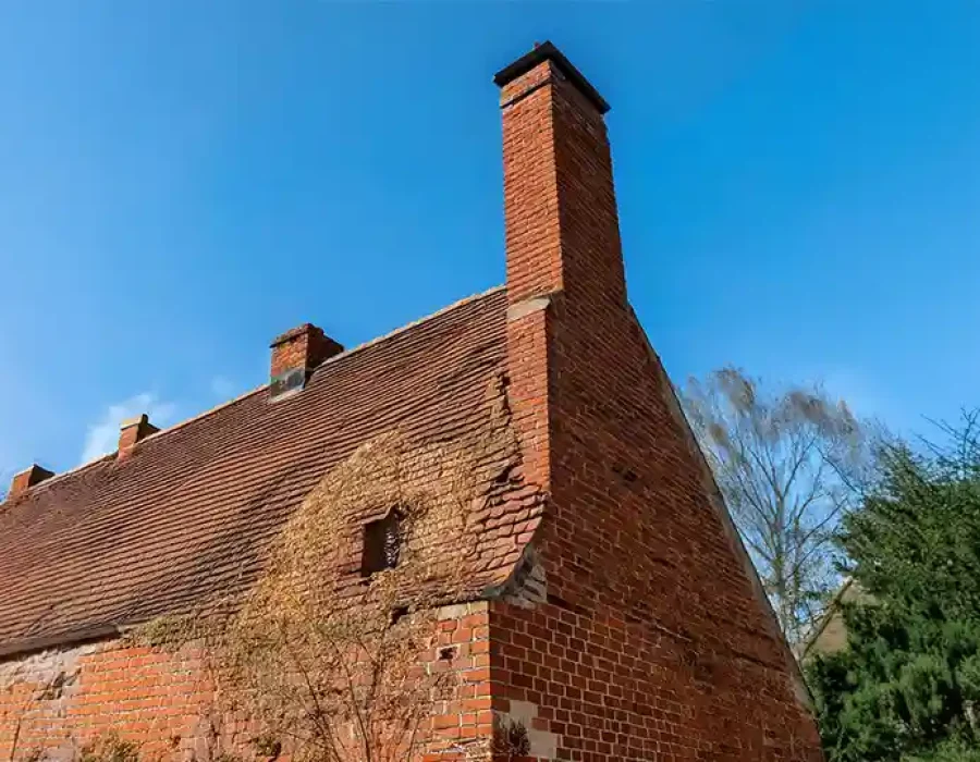 A deteriorating old brick house with visible structural damage, ideal for demolition services.