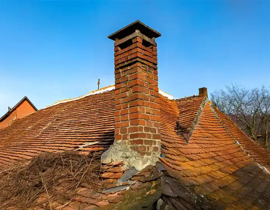 Old roof with damaged chimney requiring demolition services.