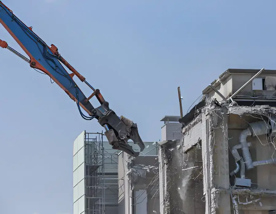 High-reach demolition machine destroying multi-story building, industrial deconstruction process