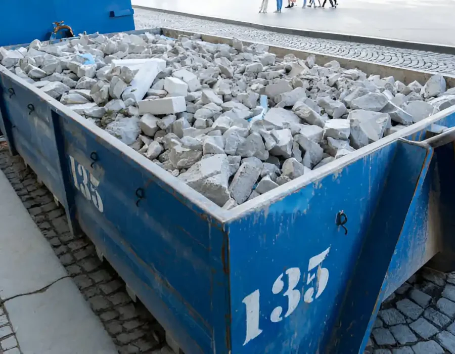Blue bin filled with construction debris and rubble for removal.