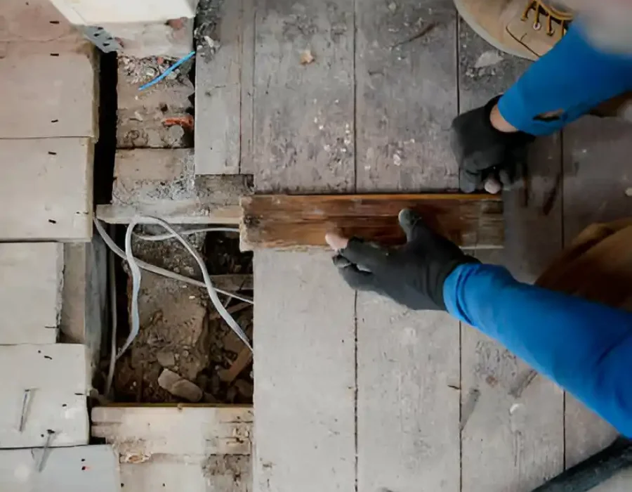 Worker removing floorboards for site cleanup
