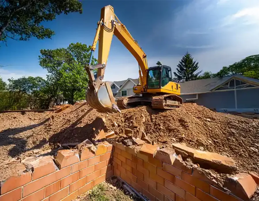 Heavy machinery demolishing a structure and clearing debris, highlighting professional demolition and cleanup solutions.
