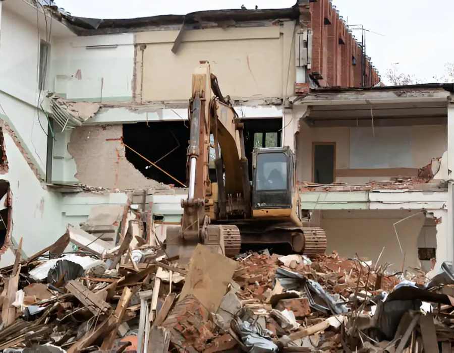 Excavator demolishing a building amid debris and rubble.