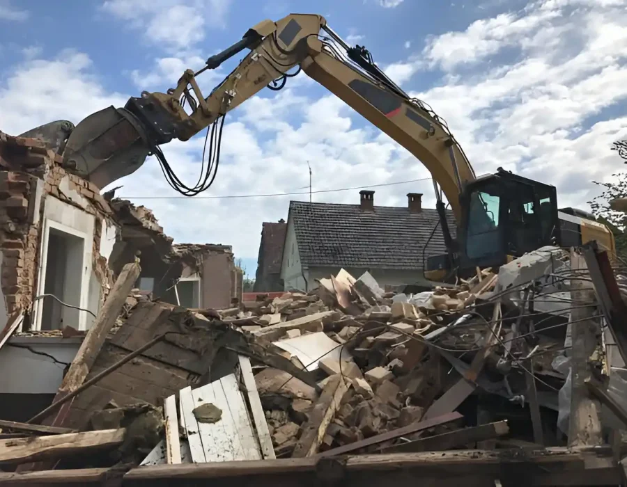 Excavator tearing down a house with rubble and debris in a residential demolition site.