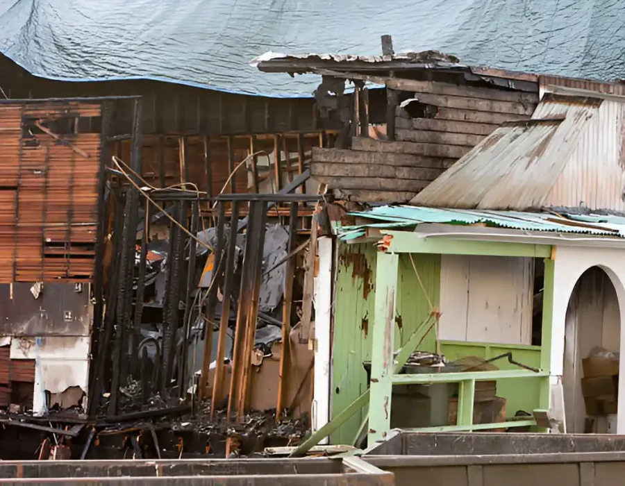 Severely fire-damaged house with charred walls and collapsed roof, ready for demolition and cleanup.