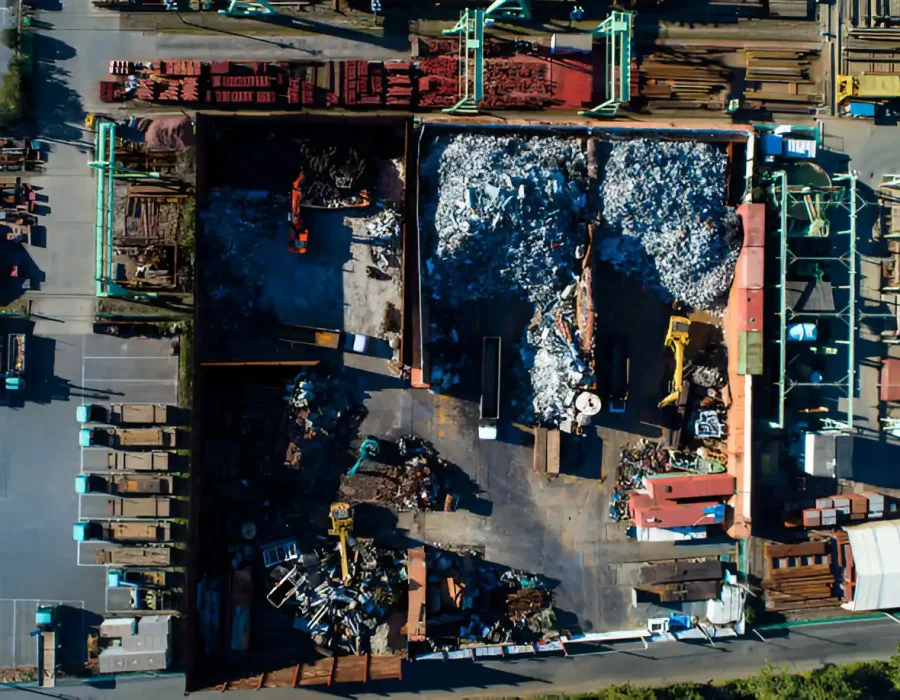 Aerial view of an industrial scrap yard with machinery and piles of metal and debris.