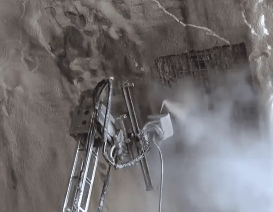 Robotic demolition equipment breaking concrete wall with dust cloud generation