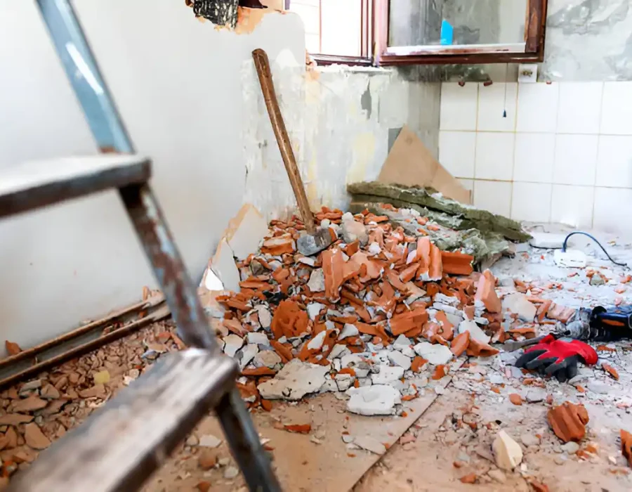 Broken tiles, construction waste, and tools scattered during kitchen demolition project