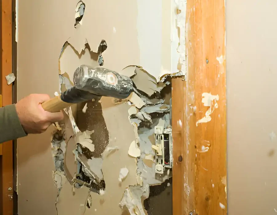 Sledgehammer breaking drywall during residential interior demolition and remodeling project